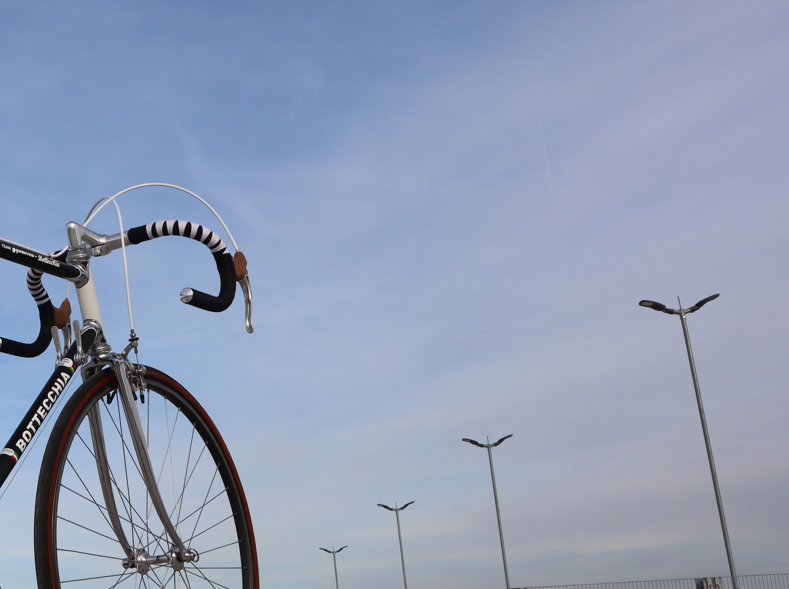 Vintage Bottecchia road bike with classic drop handlebars wrapped in black and white harlequin bar tape, photographed against a clear blue sky – Goldensteelcycles homepage.